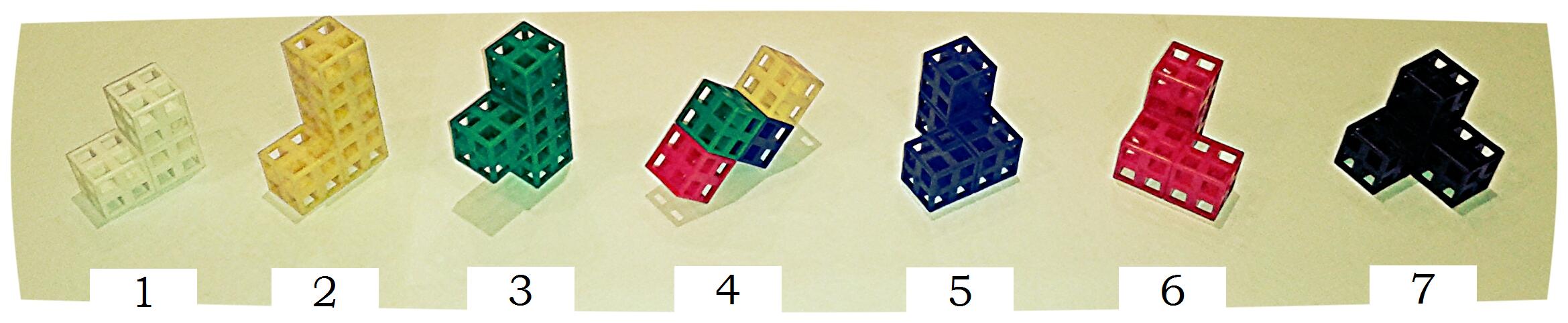 La pieza L “corta” es blanca y su número es el 1, la L es amarilla y el 2, la pieza T es verde y tiene el 3, la Z debería de ser naranja, aunque nosotros a falta de cubos naranjas la hemos fabricado multicolor, y su número es el 4, la pieza azul tiene el 5 y su imagen especular es roja con el número 6, y finalmente, la pieza esquina es negra y su número es el 7